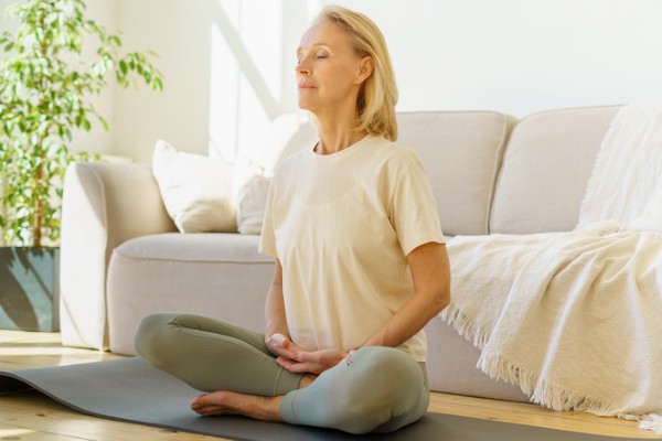 A senior woman practices controlled breathing as she meditates.