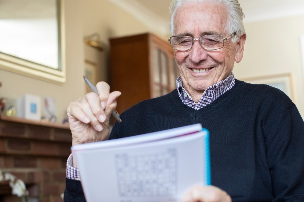A senior tries his hand at a sudoku puzzle in a book.