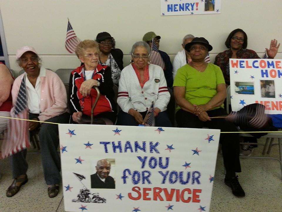 A group of people holding posters, and thanking their friend for his service