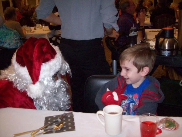 Young boy at Christmas Party talking to Santa Claus
