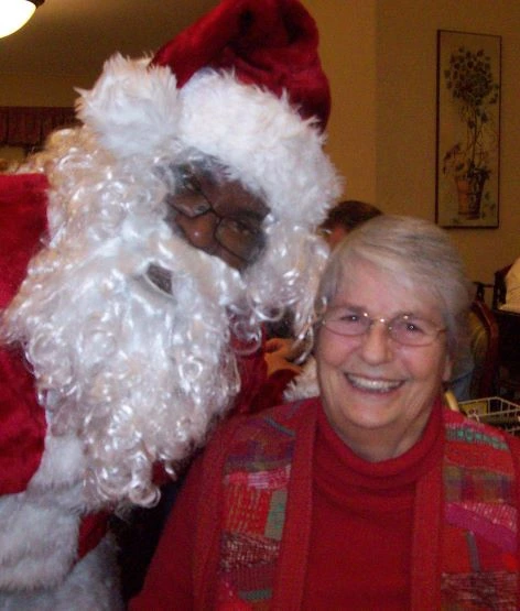 A women smiling while sitting next to Santa Claus