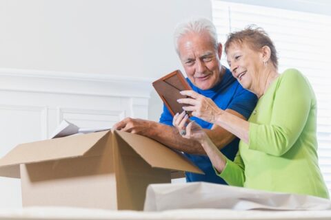 A couple reflects on a photograph as they pack a box before moving.