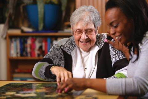 woman smiling and doing puzzle