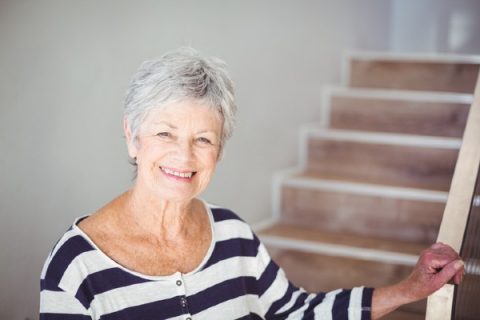 A senior woman stands in front of a stairway, a prime location for a fall.