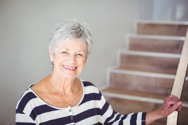 A senior woman stands in front of a stairway, a prime location for a fall.