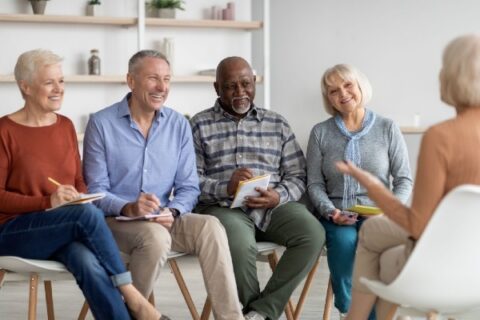 A group of seniors participating in a support group while gathered in a circle.