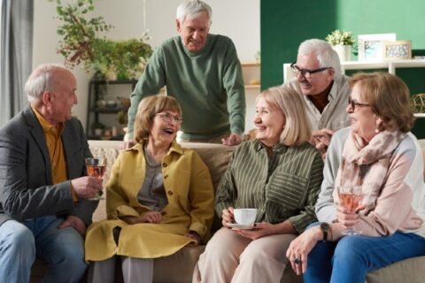A group of seniors in a retirement community talk and laugh together.