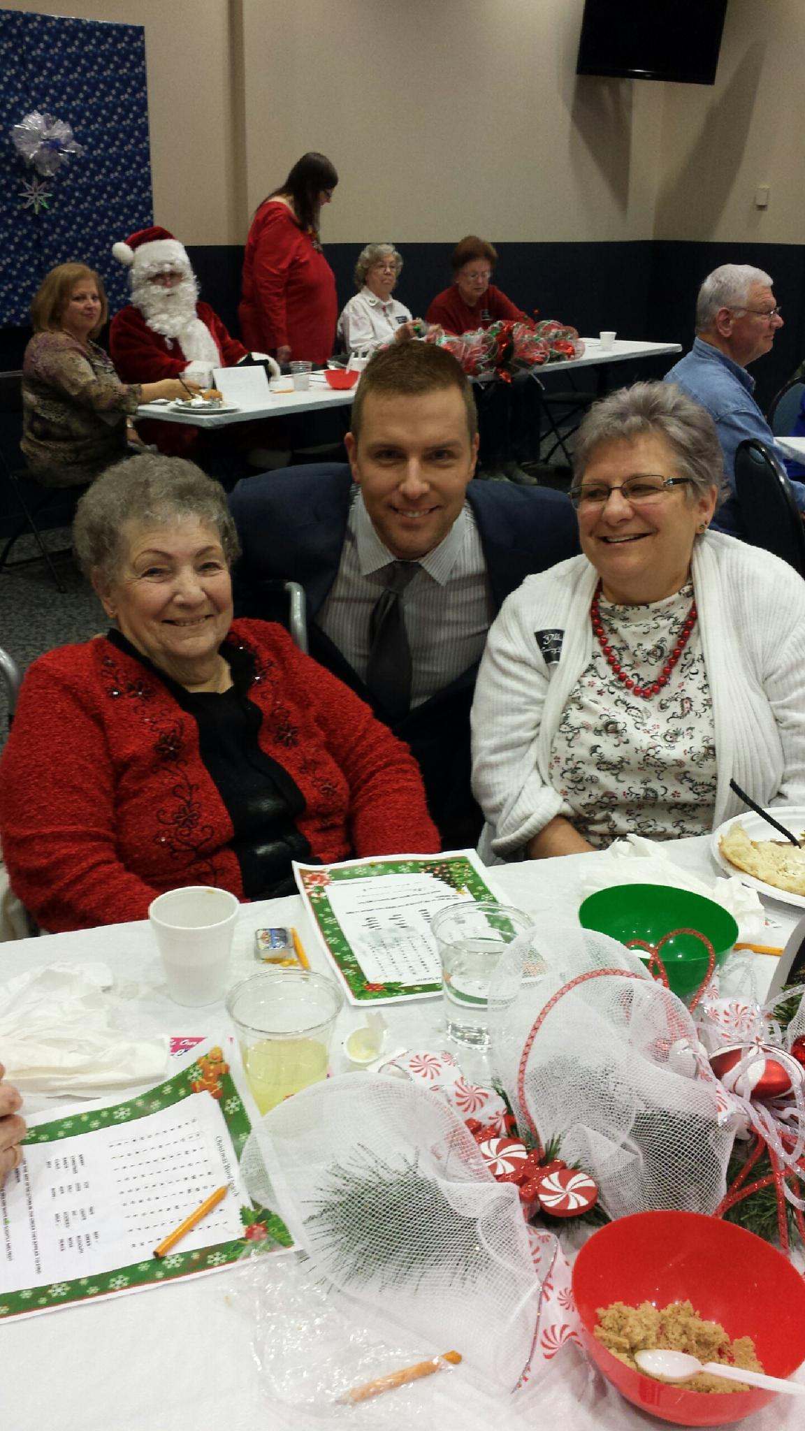 Arvada Harrington and her daughter Debbie Case smile for a photo with entertainer Johnny Steiner at the Windsor Senior Annual Christmas Potluck held at the Union County Building in Marysville, Ohio