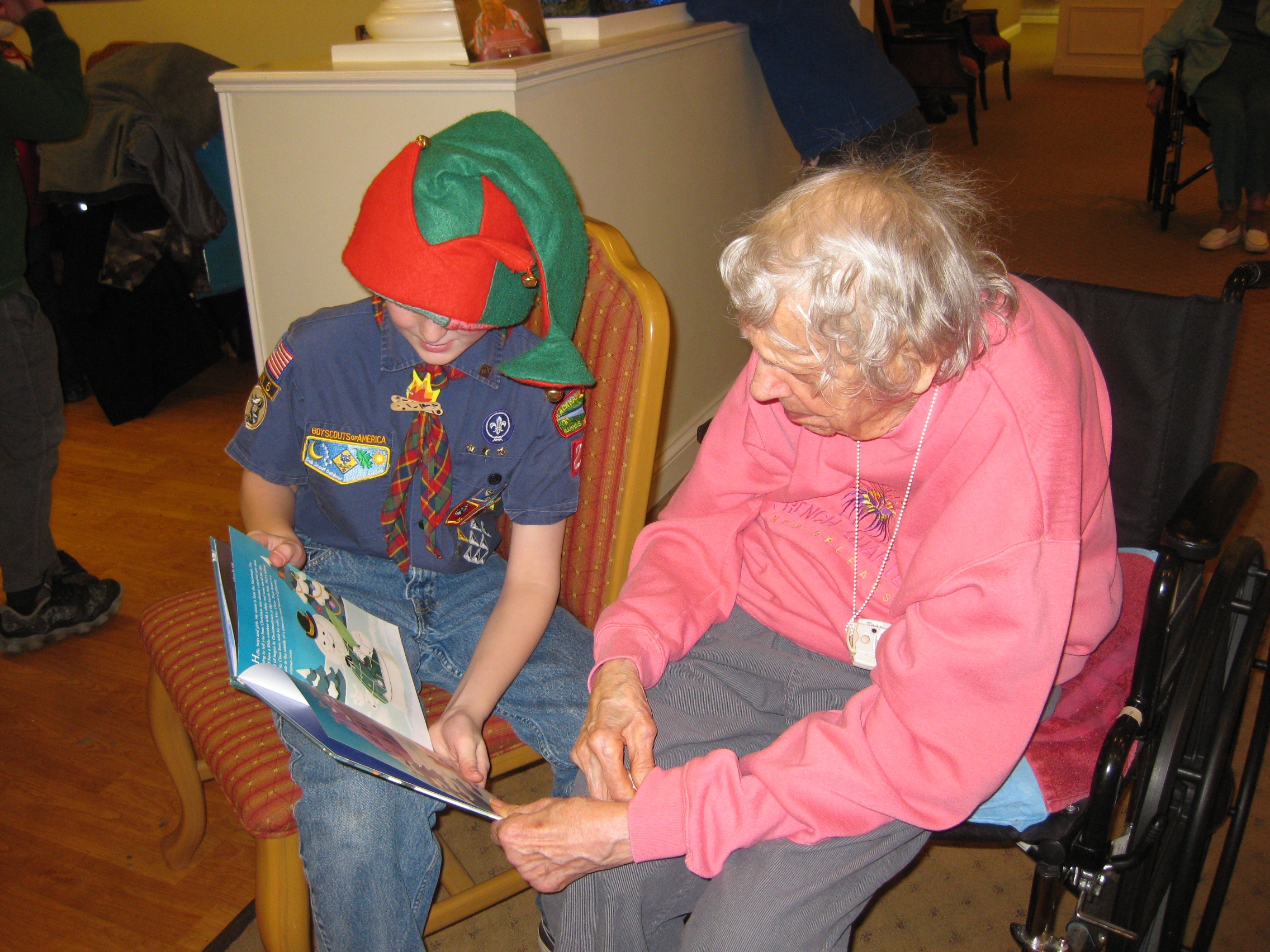 Dorothy reads a Christmas book with a Cub Scout