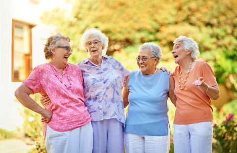 four older women standing outside of a senior living community