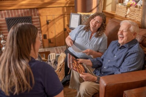 Child caregiver and their senior father meeting with a senior living community team member.