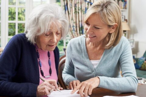 A woman helps her aging mother fill out a form.