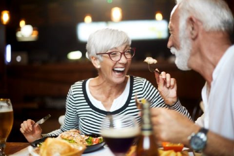 Older adult couple laughing while eating dinner