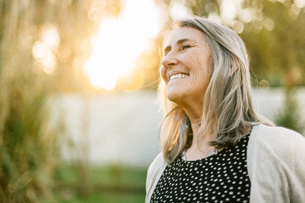 Senior woman smiling outside in the sunlight