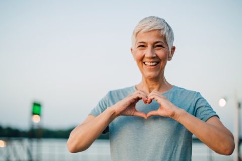 Healthy adult woman walking outside making a heart with her hands
