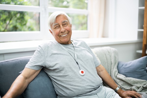 Senior man sitting and smiling with a medical device alert lanyard