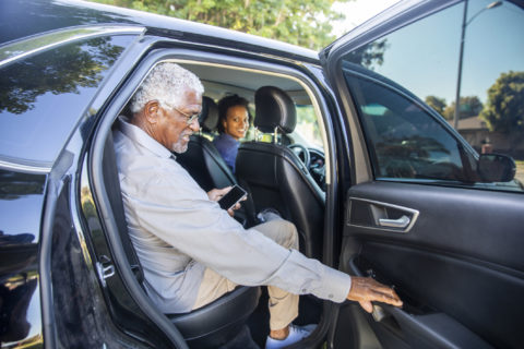 Senior getting into the backseat of a car