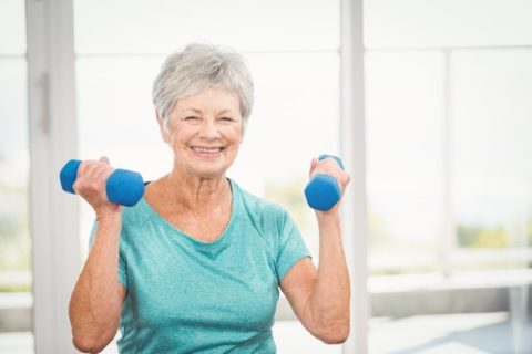 A senior woman exercises with weights to stay healthy