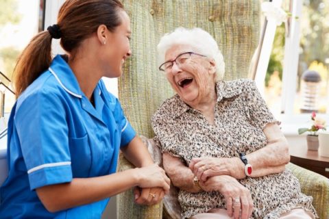 Senior caregiver laughing with an older adult
