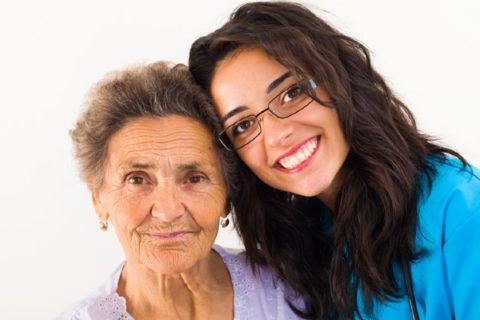 A senior woman with dementia is cared for by a young nurse.