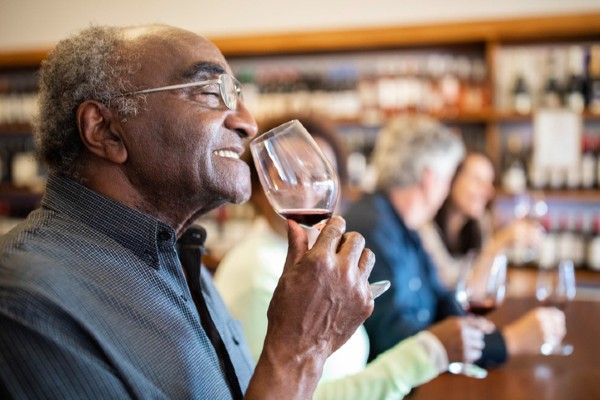 A senior man enjoys the bouquet of a wine during a tour.