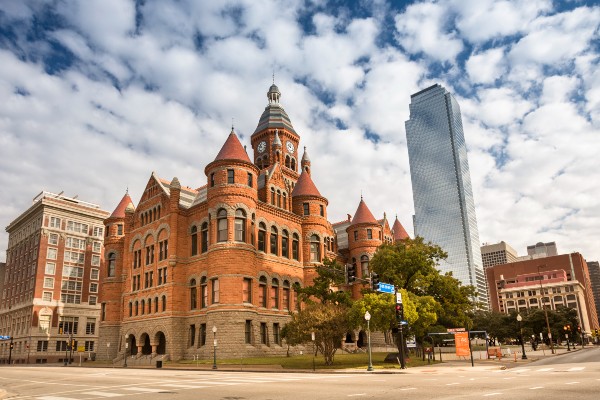 The historic Dallas County Courthouse in the foreground contrasts with a skyscraper in the background.