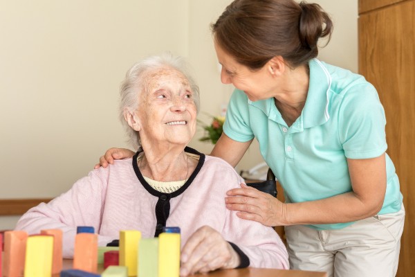 A senior woman with dementia is comforted by a caregiver.