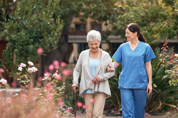 A senior in assisted living enjoys a walk with an attendant at a senior community.