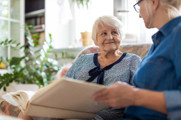 A senior woman looks at a photo album with her daughter.