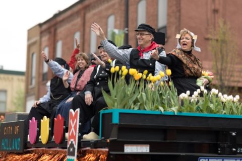 Women and men wearing traditional Dutch clothing ride in a parade during the Tulip Time Festival.