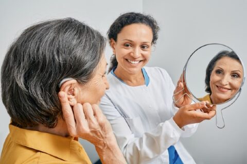 A senior woman is fitted for a hearing aid.