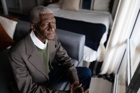 A senior man gazes out a window.