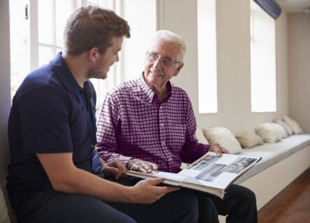 mc image Elderly man looking at book with friendly nurse