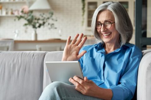 An older woman in senior care communicates to her family through a tablet.