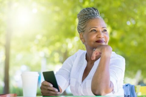 A senior woman waits for a friend in the park.