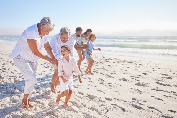 An active senior couple visits the beach with their grandchildren and children.