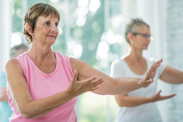 Senior women practice tai chi in a workout room.