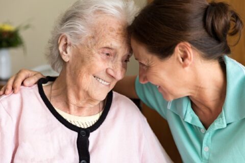A woman with dementia gets assistance from a caregiver.