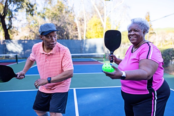 Two seniors get ready to serve during a pickleball game.