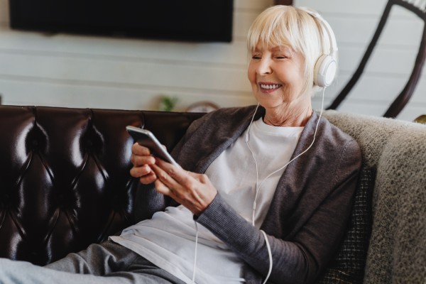 A senior woman enjoys a podcast from her phone.