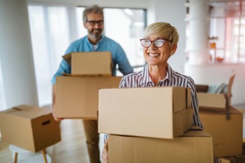 A happy older couple gets some boxes ready for the move.