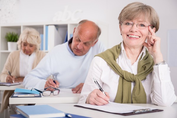 A senior woman and her friends learn in a classroom.