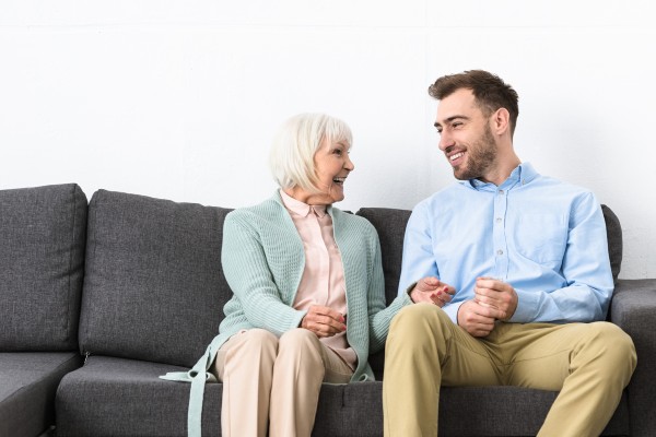 A senior woman looks at her son while seated on a couch.