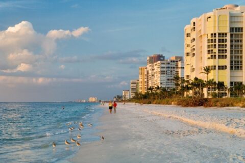 A couple walks along the beach in Naples, FL.