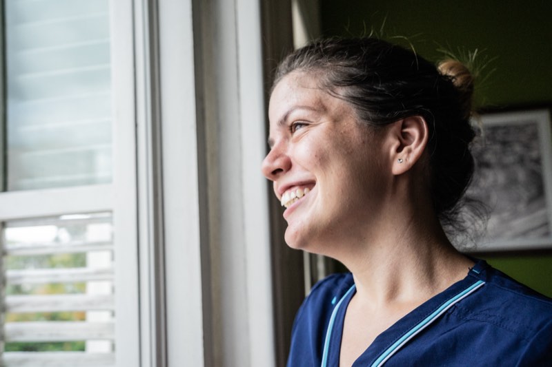 Female home caregiver contemplating and looking through the window at nursing home