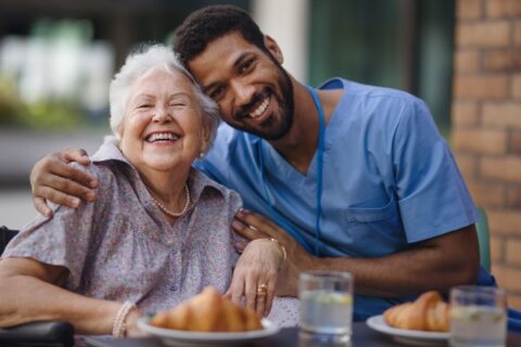 A caregiver has breakfast with his senior client.