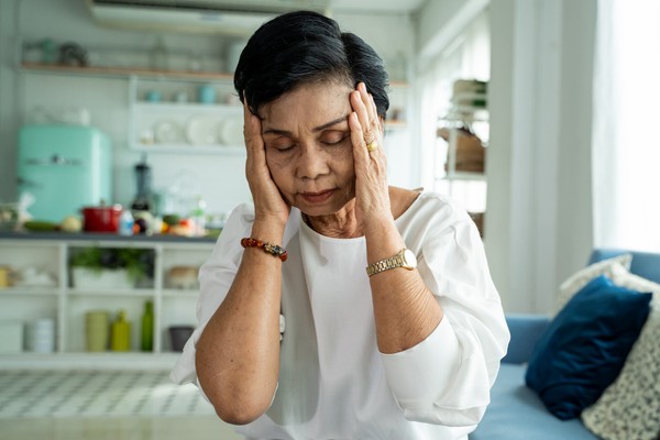 A senior Asian woman experiences a migraine.