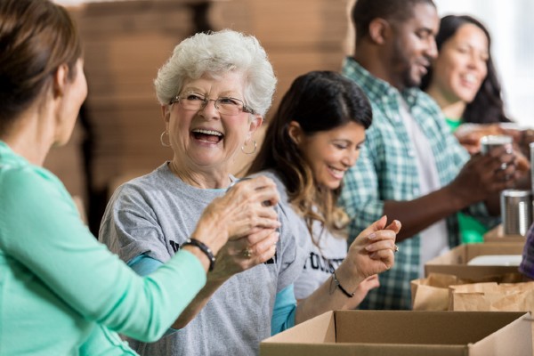 A senior woman smiles while volunteering with a group of people.