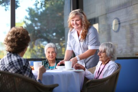 Team member providing 3 female residents coffee and snacks.