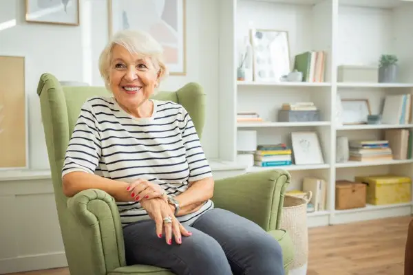 A senior woman sitting in an armchair in her apartment.